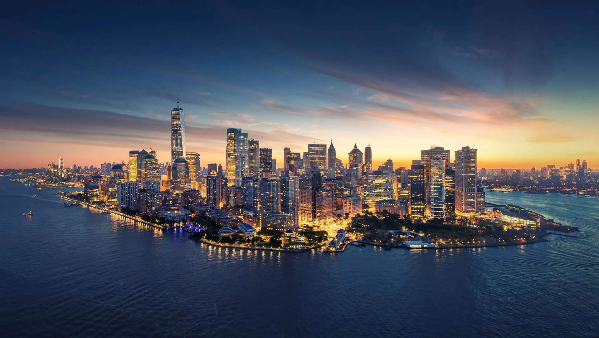 A panoramic view of Manhattan in New York in the warm sunset and the building brightly lit.