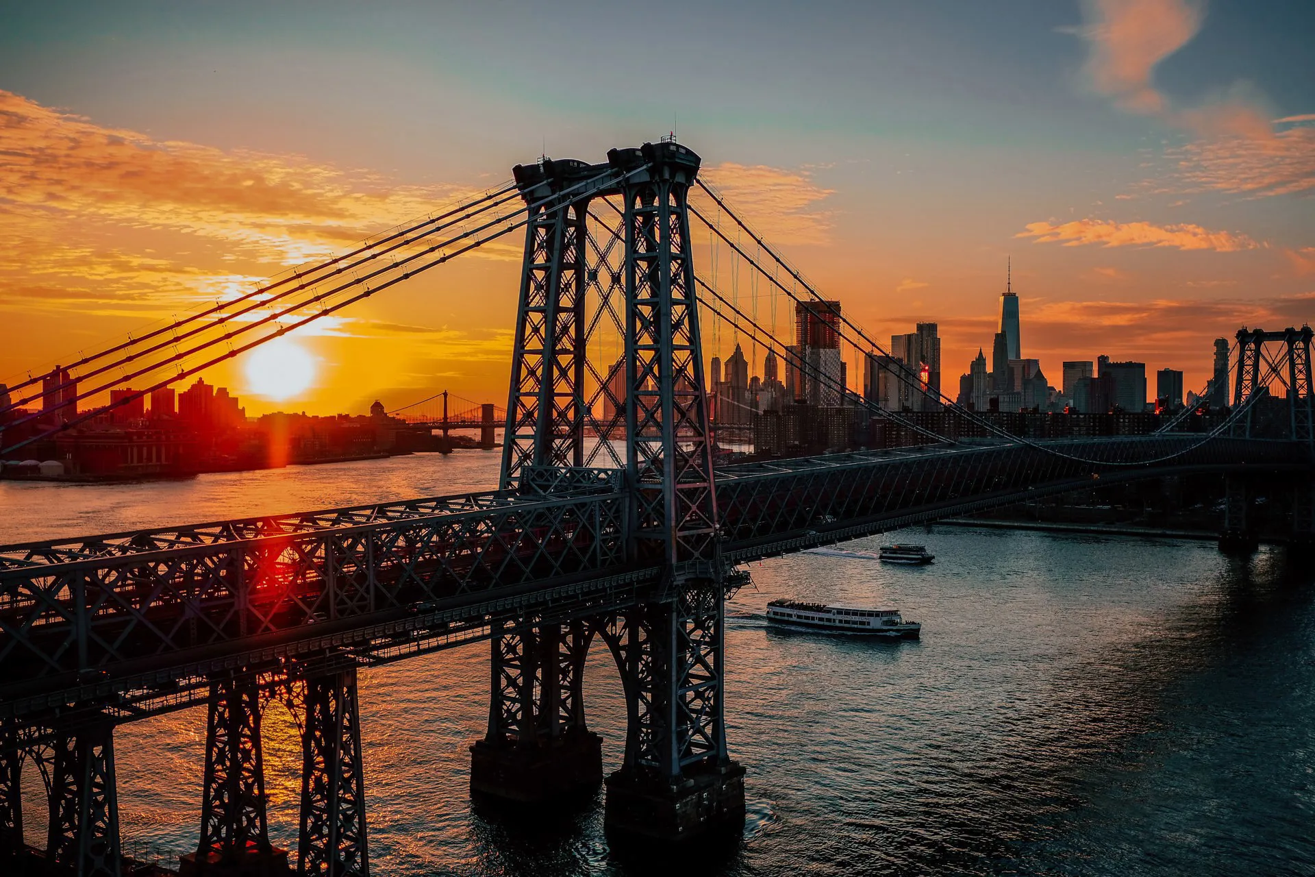 A bridge in New York City with a sunset behind it.