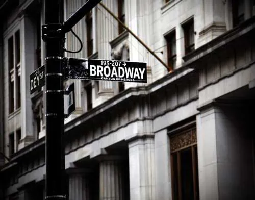 A signpost labelled 'Broadway' in front of a stone building with pillars.