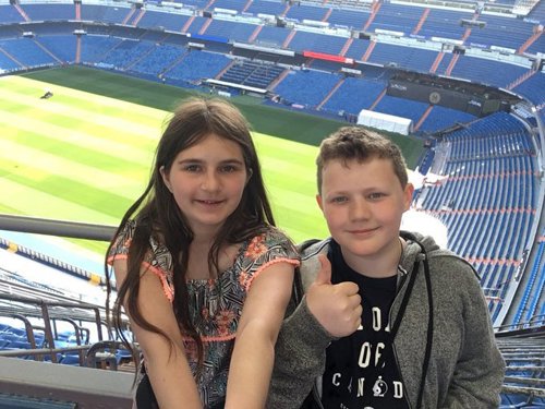 Two students smiling in front of the field at Barcelona Football Stadium, also known as Lluis Companys Olympic Stadium.