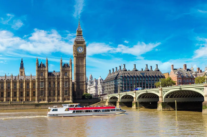 Boat cruising on the River Thames past Big Ben and Houses of Parliament